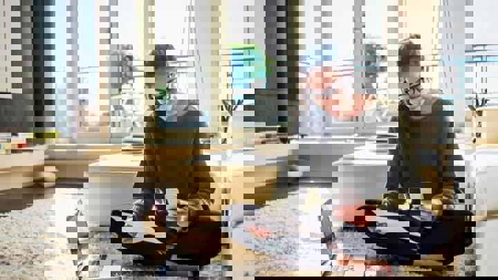 Person sititng down looking at their phone holding a piece of paper.